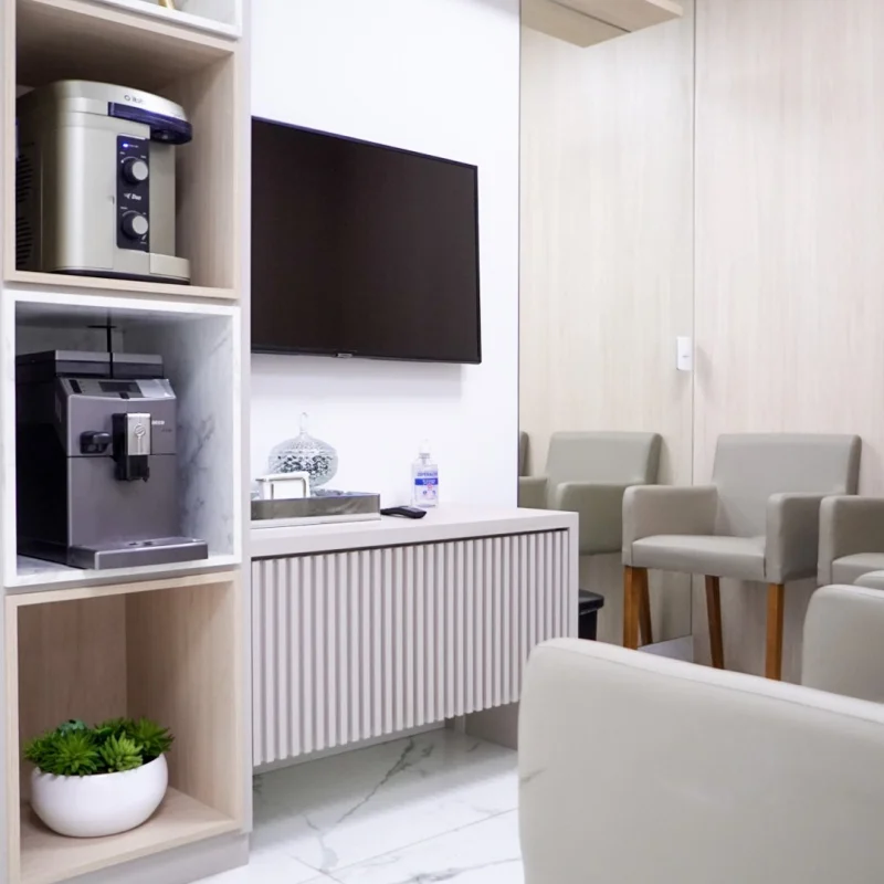 Sala de espera da Amabi Odontologia, com poltronas, TV e estação de café